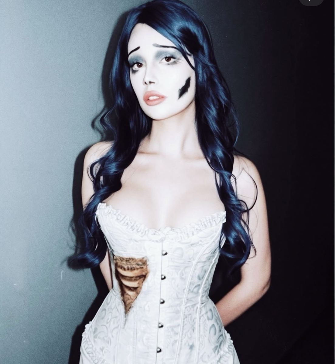 Dead bride character with blue hair, pale painted skin and an open corset wound