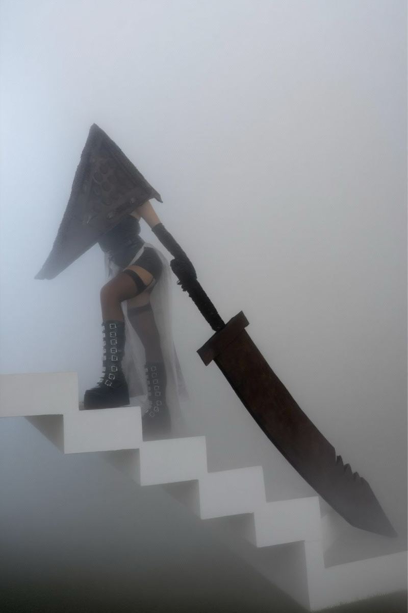 Masked executioner cosplay with a built helmet and oversized blade on a staircase in fog
